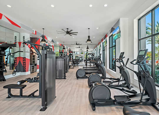 a gym with cardio equipment and windows in a building at Altis Grand Suncoast, Land O' Lakes Florida