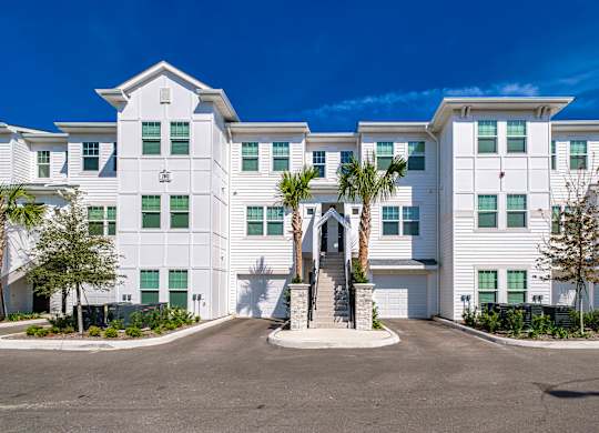a large white building with palm trees in front of it at Altis Grand Suncoast, Land O' Lakes, 34638