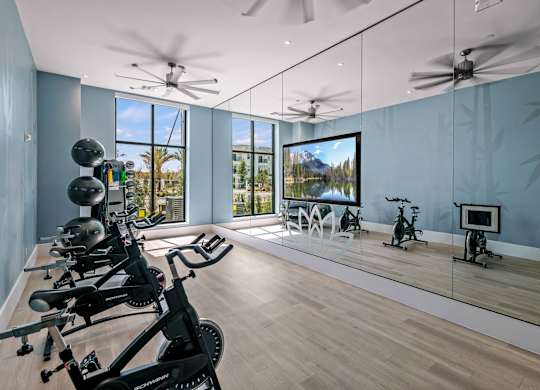 a workout room with mirrors and weights on a wooden floor at Altis Grand Suncoast, Land O' Lakes, 34638