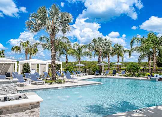 A pool surrounded by palm trees and lounge chairs.