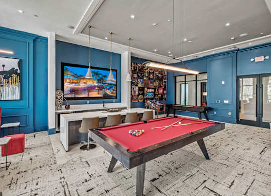 a game room with a red pool table and a television at Altis Twin Lakes Apartments, Kissimmee, FL 34744