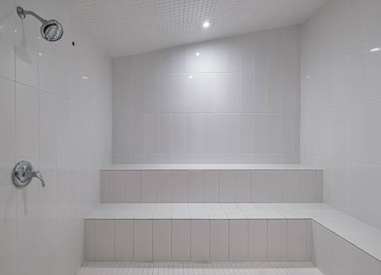 a white bathroom with a shower and white tiles  at Altis Grand Suncoast Apartments, Florida