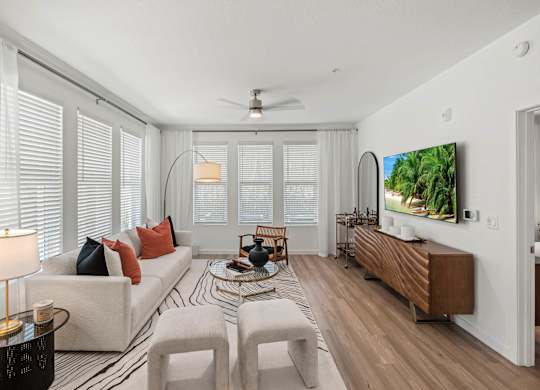 A living room with a white couch, a coffee table, and a television on the wall.