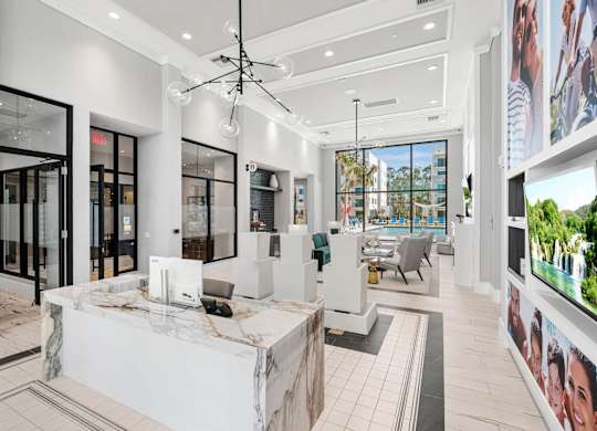 A modern office lobby with a reception desk and a large screen on the wall.