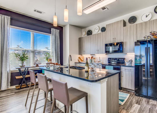 Two Bedroom Apartments in Lewisville, TX - Hebron 121 Station - Modern Kitchen with Large Island, Stainless Steel Appliances, and Granite-Style Countertops.