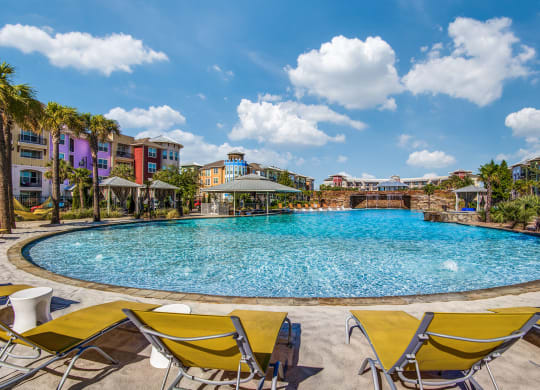 Apartments in Lewisville TX- Exterior Image of Hebron 121 Station's Expansive Pool with Yellow Chaise Chairs, Cabanas, and Gazebo