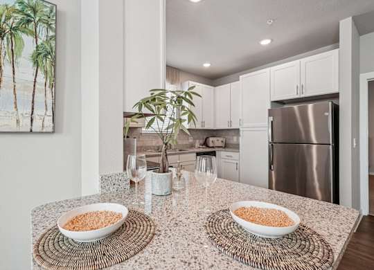 A kitchen with a table topped with bowls of cereal and a potted plant.