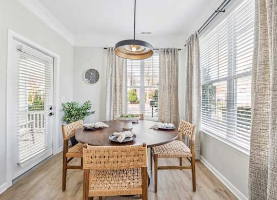 A dining room with a table set for two and a view of the backyard.