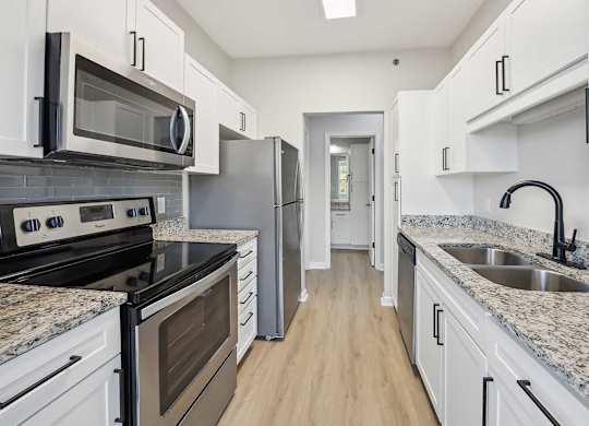 A kitchen with white cabinets and granite countertops.