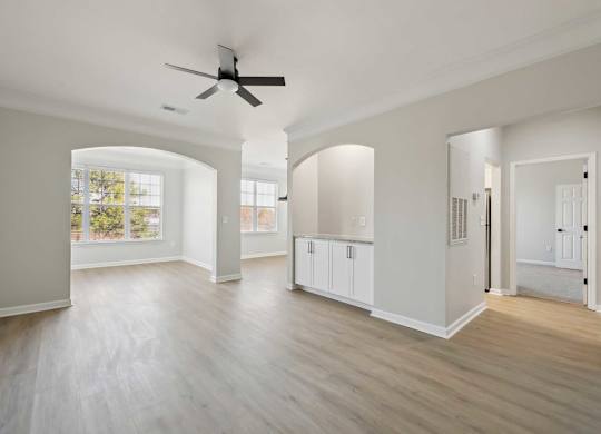 A spacious room with a ceiling fan and light wood flooring.