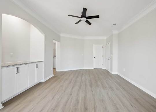 A spacious room with a ceiling fan and light wood flooring.