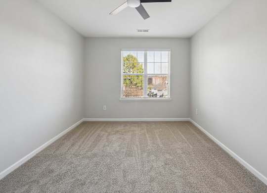 A room with a window and a fan on the ceiling.