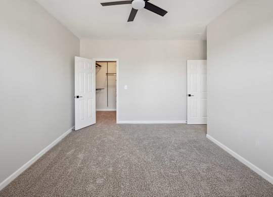 A room with a ceiling fan and carpeted floor.