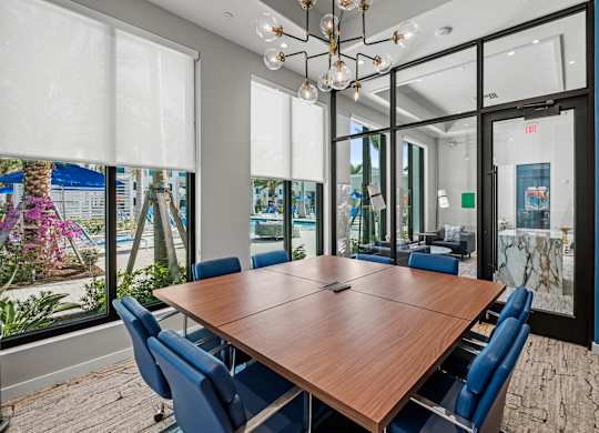 A conference room with a long table and chairs, a chandelier, and a view of the outside through the windows.