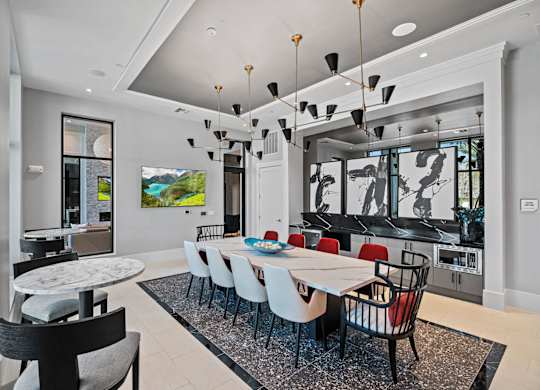 a dining room with a long white table and chairs and a kitchen in the background at Altis Twin Lakes Apartments, Kissimmee, 34744