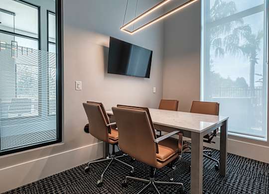 a conference room with a table and chairs and a tv at Altis Grand Suncoast, Land O' Lakes, FL