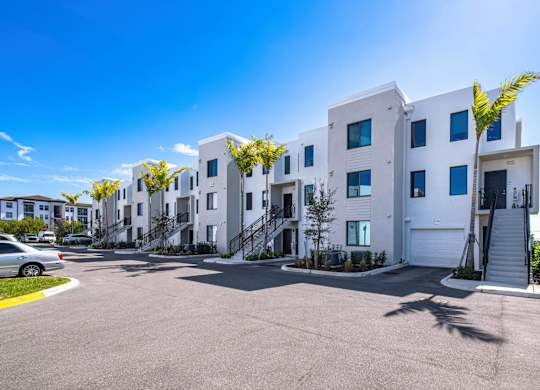A row of white townhouses with a car parked in front.