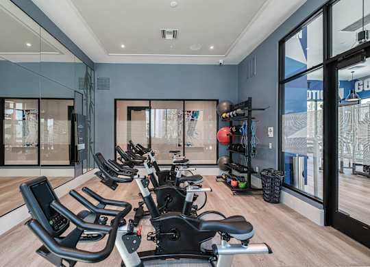 a home gym with a row of chairs in front of windows at Altis Santa Barbara, Florida