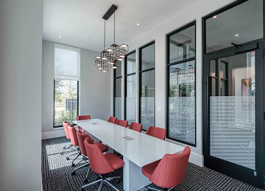 a long table with red chairs in a room with large windows at Altis Twin Lakes Apartments, Kissimmee, FL