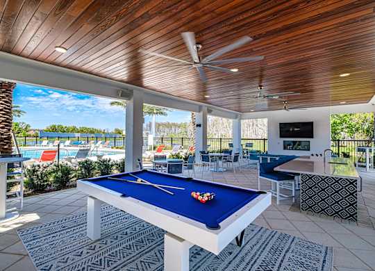 a pool table in a covered patio with a view of the pool and the beach at Altis Grand Suncoast, Land O' Lakes, 34638