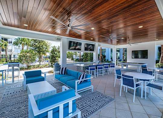 a lounge area with blue chairs and tables and a pool at Altis Grand Suncoast, Florida, 34638