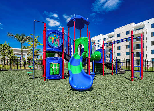 a playground with a slide and other play equipment in front of a building at Altis Santa Barbara, Naples, 34104