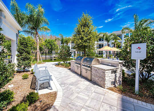 a patio with a grill and a bench next to a building at Altis Twin Lakes Apartments, Florida