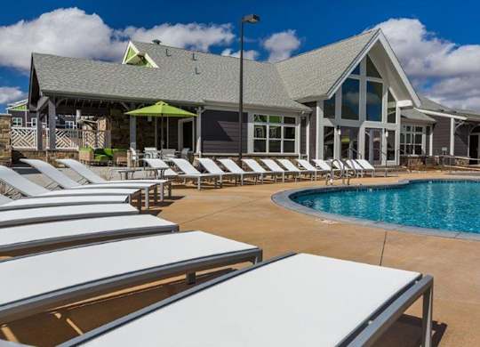 A poolside area with sun loungers and a building in the background.