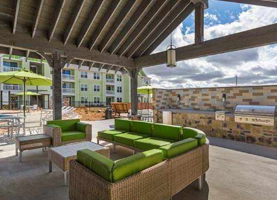 A patio with green couches and a stone wall.