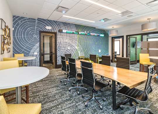 A conference room with a white table surrounded by yellow chairs.