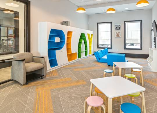 A room with a white table and chairs and a large PLAY sign.