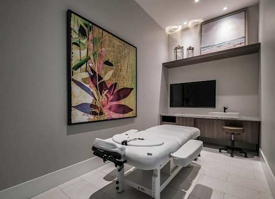 a spa room with a massage table and a tv at Altis Santa Barbara, Florida, 34104