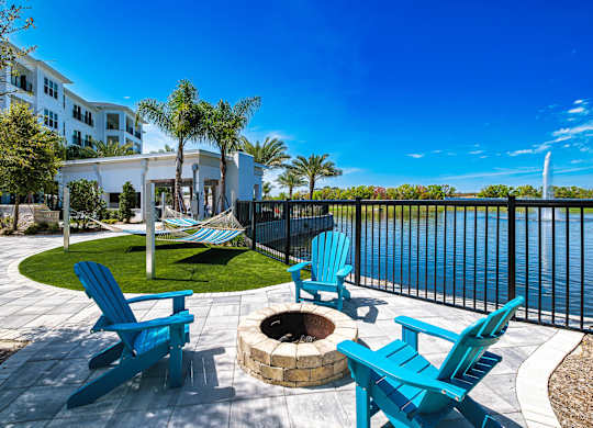 a patio with chairs and a fire pit overlooking a body of water at Altis Grand Suncoast, Florida, 34638