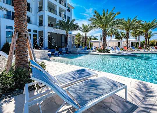 a swimming pool with lounge chairs and palm trees at Altis Twin Lakes Apartments, Kissimmee, Florida