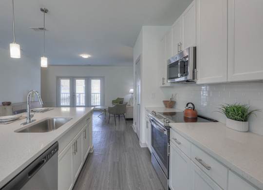 A modern kitchen with white cabinets and a wooden floor.