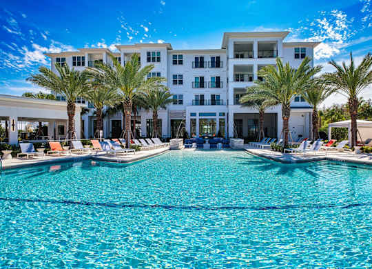 a large swimming pool with palm trees in front of a building at Altis Twin Lakes Apartments, Kissimmee, 34744