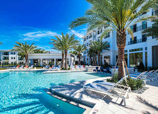 a large swimming pool with palm trees in front of a building at Altis Twin Lakes Apartments, Kissimmee