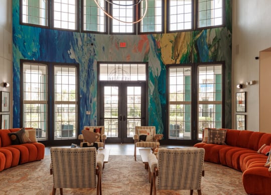 a living room with orange couches and chairs and a large wall mural