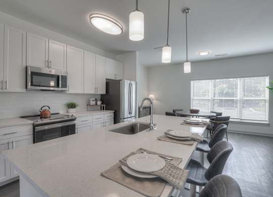 A modern kitchen with a large island and a dining table set for a meal.