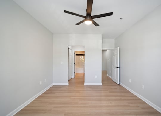 a living room with white walls and a ceiling fan