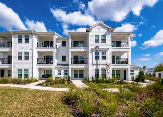 A white apartment building with balconies and a clear blue sky.