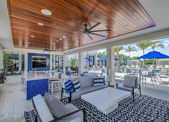a patio with couches tables and chairs and a bar at Altis Santa Barbara, Florida, 34104