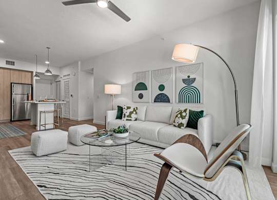 A modern living room with a white sofa, a glass coffee table, and a striped rug.