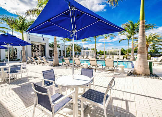 a patio with tables and chairs and umbrellas next to a pool at Altis Santa Barbara, Naples