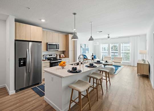a kitchen and living room with a large island with stools at Altis Grand Suncoast, Land O' Lakes, 34638