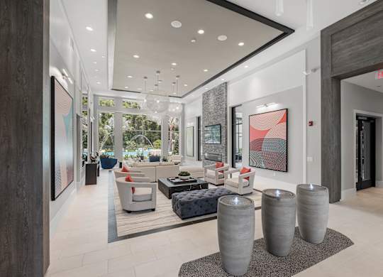 A modern living room with a large window, a couch, and a painting on the wall.