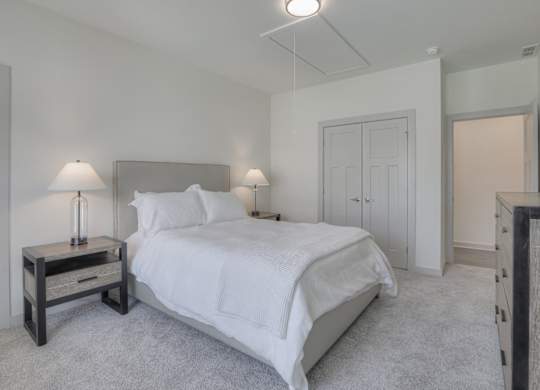 East Nashville, TN Pet-Friendly Luxury Apartments - Flats at Laurel and Pine - Bedroom with Carpeted Flooring, Bed, Nightstands with Lamps, Dresser, Private Bathroom, and Spacious Closet.