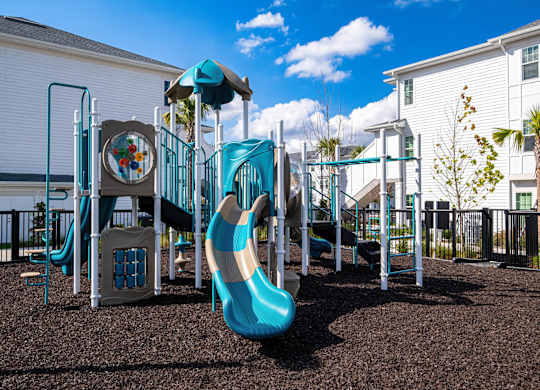 A playground with a blue slide and a brown ground.