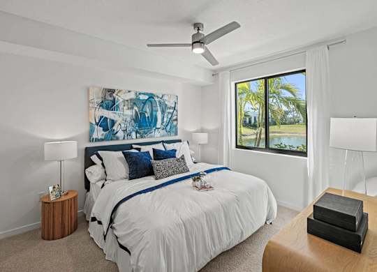 A bedroom with a large bed and a painting on the wall.