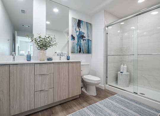 A bathroom with a toilet, sink, and a painting on the wall.